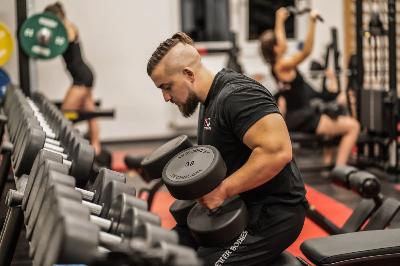 Krafttraining mit Kurzhanteln im Kraftraum der Akademie