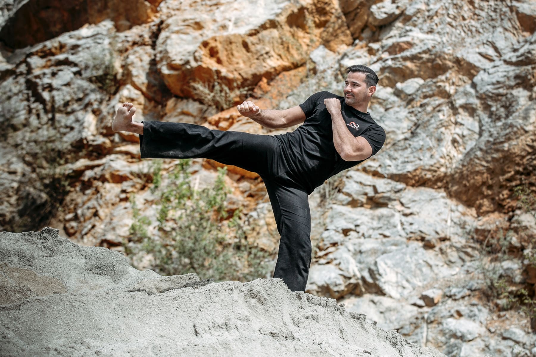 Seitwärtskick (Taekwondo, Kickboxen, Thaiboxen) auf felsigem Untergrund im Freien, ausgeführt von einem Kampfsportler der Akademie für Selbstverteidigung, Kampfkunst und Kampfsport in Graz.