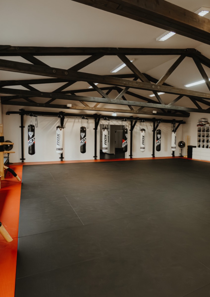Trainingshalle der Akademie für Selbstverteidigung, Kampfkunst und Kampfsport in der Koschatgasse in Graz mit Matten und Sandsäcken.